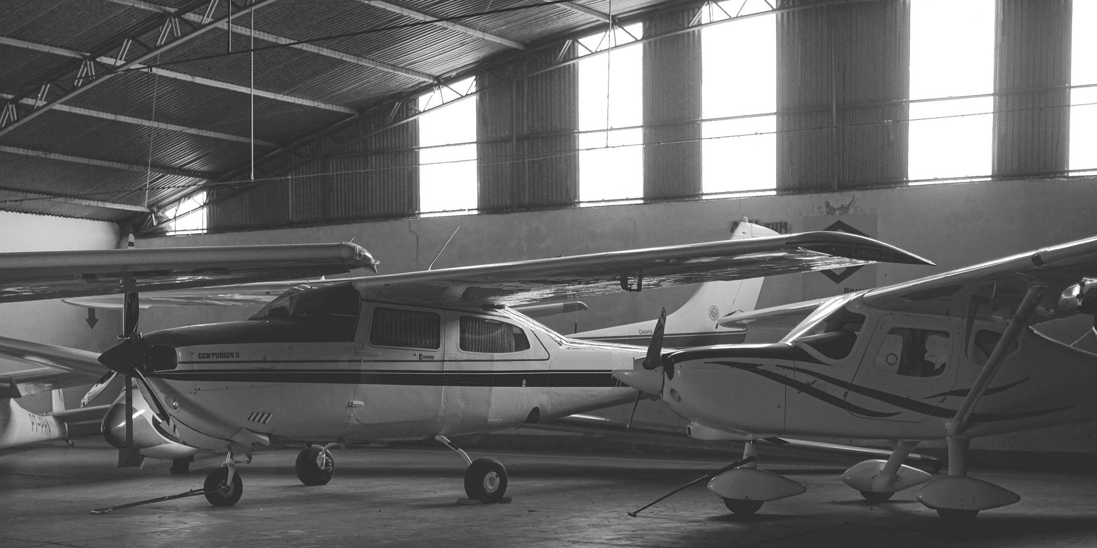 Two Cessna piston airplanes parked in a hangar, in black and white