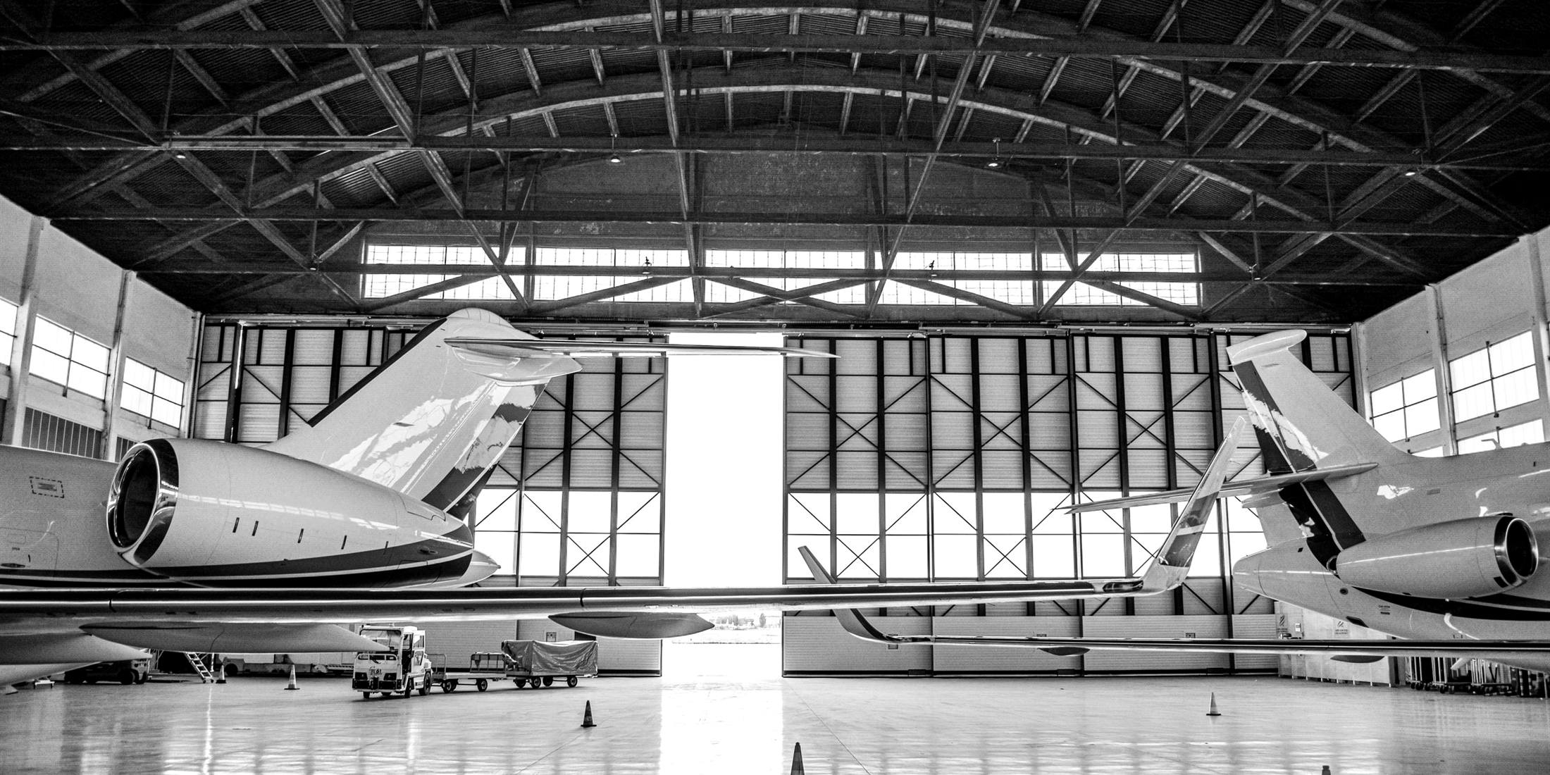 Two private jets parked in a hangar, in black and white